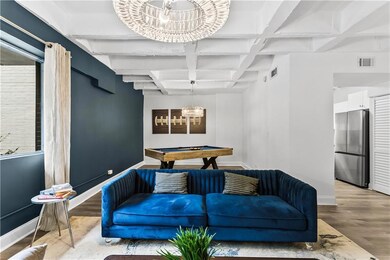 Living room featuring beamed ceiling, coffered ceiling, wood finished floors, a chandelier, and billiards table