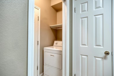Laundry area with washer / clothes dryer and a textured wall