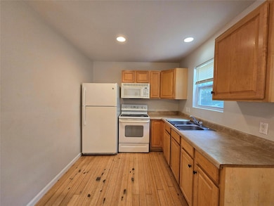 Kitchen with white appliances, light wood-type fl