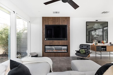 Living room with visible vents, a ceiling fan, fi