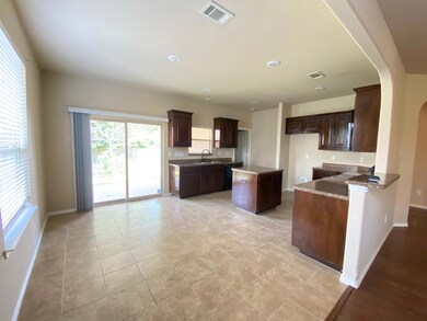Kitchen with a center island, sink, dark brown cabinets, and light tile floors