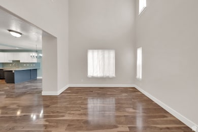 Unfurnished living room featuring a chandelier, a towering ceiling, and dark wood-style flooring