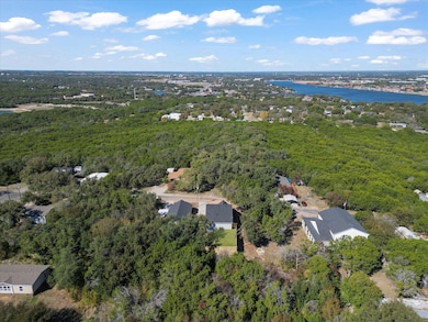 Aerial overview of property's location with a nearby body of water and a heavily wooded area