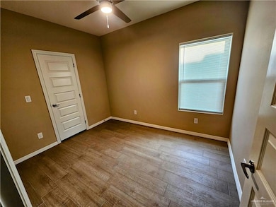 Unfurnished room featuring baseboards, ceiling fan, and dark wood finished floors