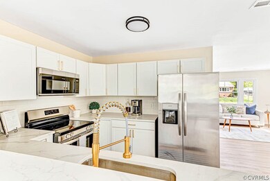 Kitchen with light stone countertops, stainless steel appliances, light hardwood / wood-style flooring, and white cabinets