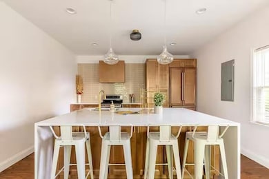 Kitchen featuring pendant lighting, sink, electric panel, a kitchen breakfast bar, and a large island with sink