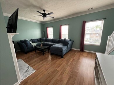 Living room featuring light wood-type flooring, crown molding, ceiling fan, a textured ceiling, and baseboards