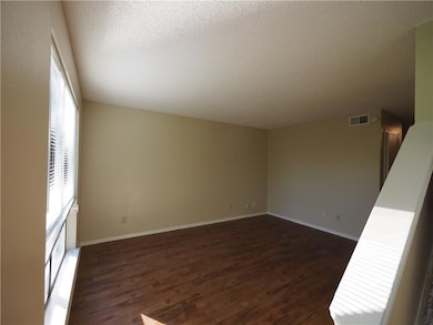 Unfurnished room with a textured ceiling, dark wo
