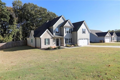 View of front of property featuring board and batten siding, a garage, driveway, and stone siding