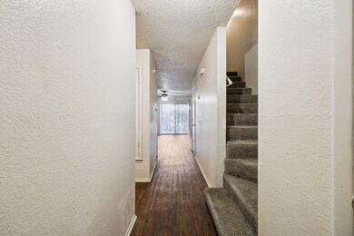 Hallway featuring a textured wall, a textured ceiling, dark wood-style flooring, and stairway