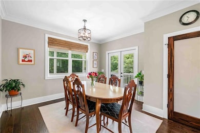 Dining room with a chandelier, ornamental molding, wood finished floors, and french doors