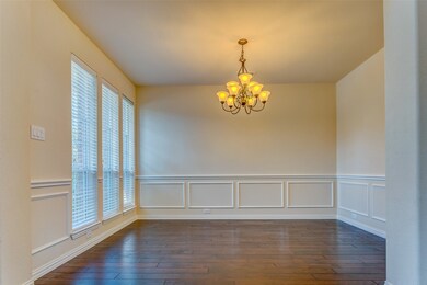 Unfurnished dining area featuring a chandelier, a decorative wall, wainscoting, and dark wood-style floors