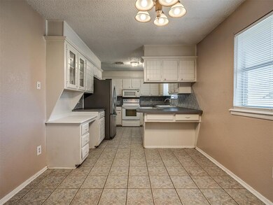 Kitchen with white cabinetry, a chandelier, tastef