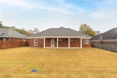 Rear view of property with roof with shingles, brick siding, a fenced backyard, and a patio