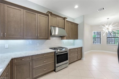 Kitchen with quartz counters, light tile flooring, elegant glass tile backsplash, and stainless steel range with gas stovetop