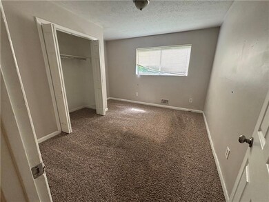 Unfurnished bedroom with carpet, a textured ceiling, baseboards, and a closet