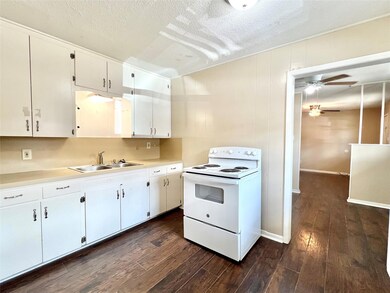 Kitchen featuring white cabinets, dark wood-type f