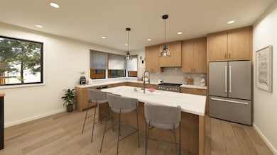 Kitchen featuring appliances with stainless steel finishes, a kitchen bar, light brown cabinetry, decorative light fixtures, and light wood-style flooring