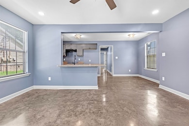 Kitchen with concrete flooring, ceiling fan, a peninsula, gray cabinetry, and extractor fan