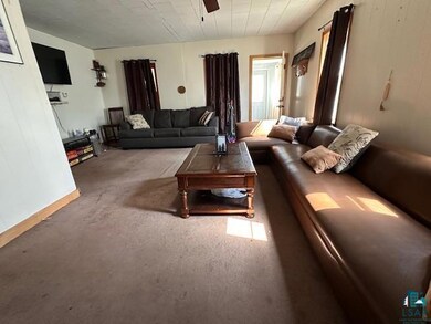 Carpeted living room featuring a ceiling fan and baseboards