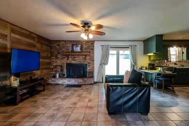 Living area featuring plenty of natural light, ceiling fan, a textured ceiling, light tile patterned floors, and wooden walls