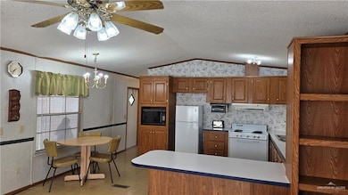 Kitchen with open shelves, crown molding, white appliances, lofted ceiling, and brown cabinetry