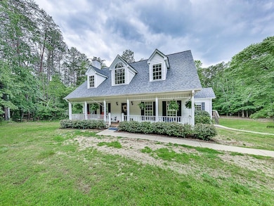 New england style home with a front yard, a porch, a shingled roof, and a chimney