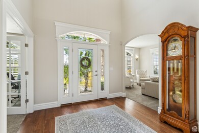Entrance foyer with arched walkways, a high ceiling, baseboards, and wood finished floors