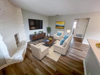 Living room with a stone fireplace, visible vents