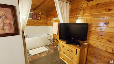 Bathroom featuring wood walls, a garden tub, and wood ceiling