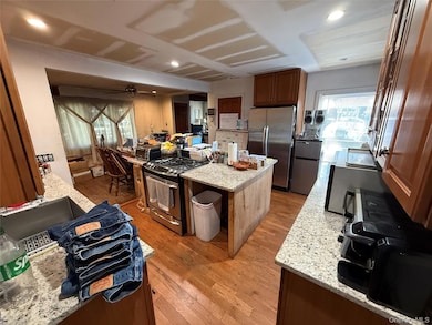 Kitchen featuring plenty of natural light, light stone counters, a center island, light wood-type flooring, and recessed lighting