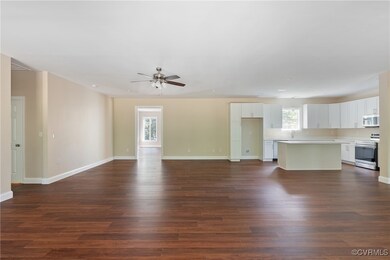 Unfurnished living room featuring dark wood-type flooring, ceiling fan, and sink