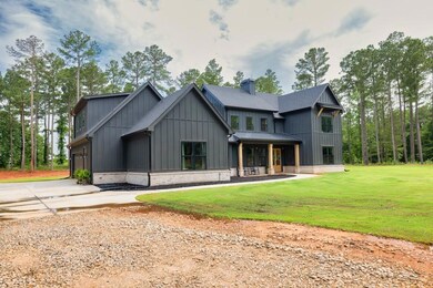 View of front of house with board and batten siding, concrete driveway, a front yard, a standing seam roof, and roof with shingles
