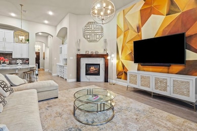 Living room featuring a chandelier, a warm lit fireplace, arched walkways, light wood-style floors, and recessed lighting