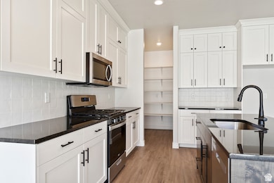 Kitchen with stainless steel appliances, recessed lighting, light wood-style flooring, backsplash, and white cabinetry