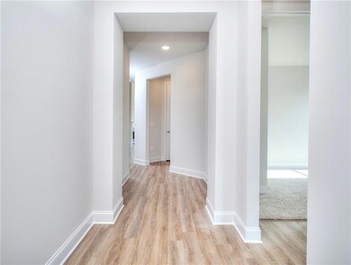 Corridor with wood-style finished floors and baseboards