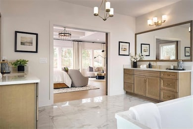 Photo from the Roswell Model Home: Bathroom featuring marble tiled flooring, a chandelier, vanity, and a freestanding tub