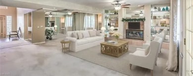Living room with concrete floors, a ceiling fan, plenty of natural light, and a glass covered fireplace
