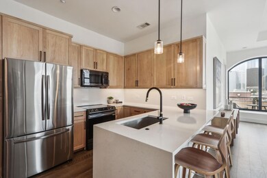 Kitchen featuring visible vents, range with electric stovetop, a sink, freestanding refrigerator, and a peninsula