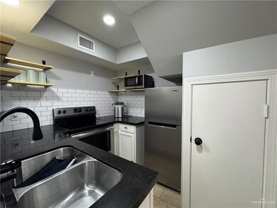 Kitchen with white cabinetry, appliances with stainless steel finishes, sink, and decorative backsplash