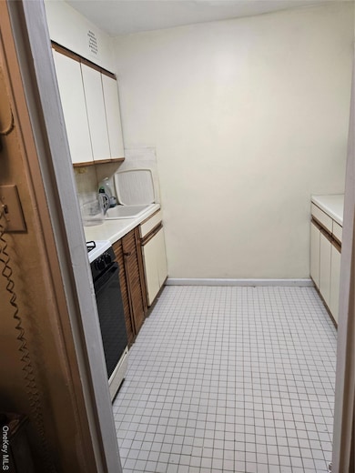 Kitchen featuring white cabinetry, stove, sink, and backsplash