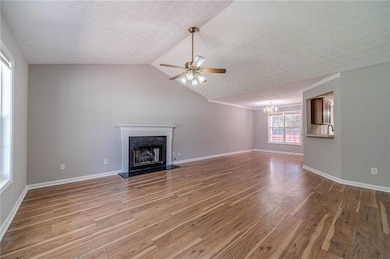 Unfurnished living room featuring light wood-style flooring, a chandelier, a premium fireplace, a textured ceiling, and ceiling fan