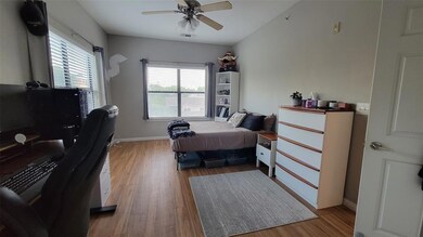 Bedroom featuring light wood finished floors, an office area, and a ceiling fan