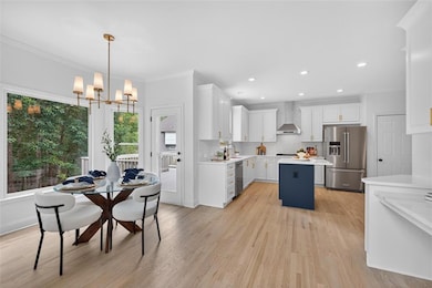 Kitchen with ornamental molding, white cabinets, stainless steel appliances, light wood-style flooring, and backsplash
