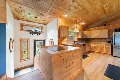 Kitchen featuring appliances with stainless steel finishes, light wood-type flooring, vaulted ceiling, wooden ceiling, and a chandelier