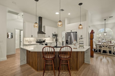 Kitchen featuring decorative backsplash, a kitchen breakfast bar, stainless steel appliances, light wood finished floors, and a spacious island