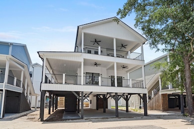 Back of house featuring a ceiling fan, a carport, and a balcony