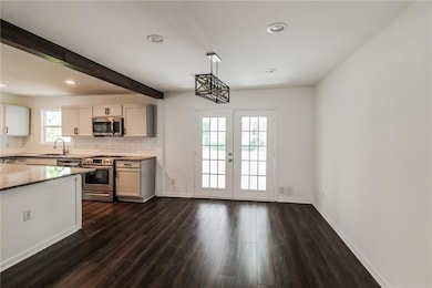 Kitchen featuring light stone counters, decorative backsplash, stainless steel appliances, and a sink