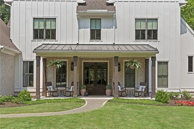A herringbone brick front porch, crowned with a stained tongue-and-groove ceiling, offers a warm welcome to the refined craftsmanship within.