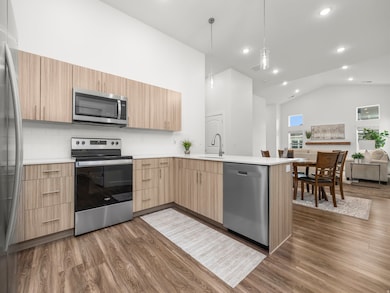Elevated kitchen with mid-tone cabinets, quartz counters, tile backsplash, and stainless steel appliances. *Refrigerator not included.
